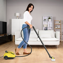 Woman cleaning a wooden floor with the yellow steam cleaner