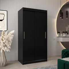 The black sliding door wardrobe has two mirrored doors and stands in a bedroom setting