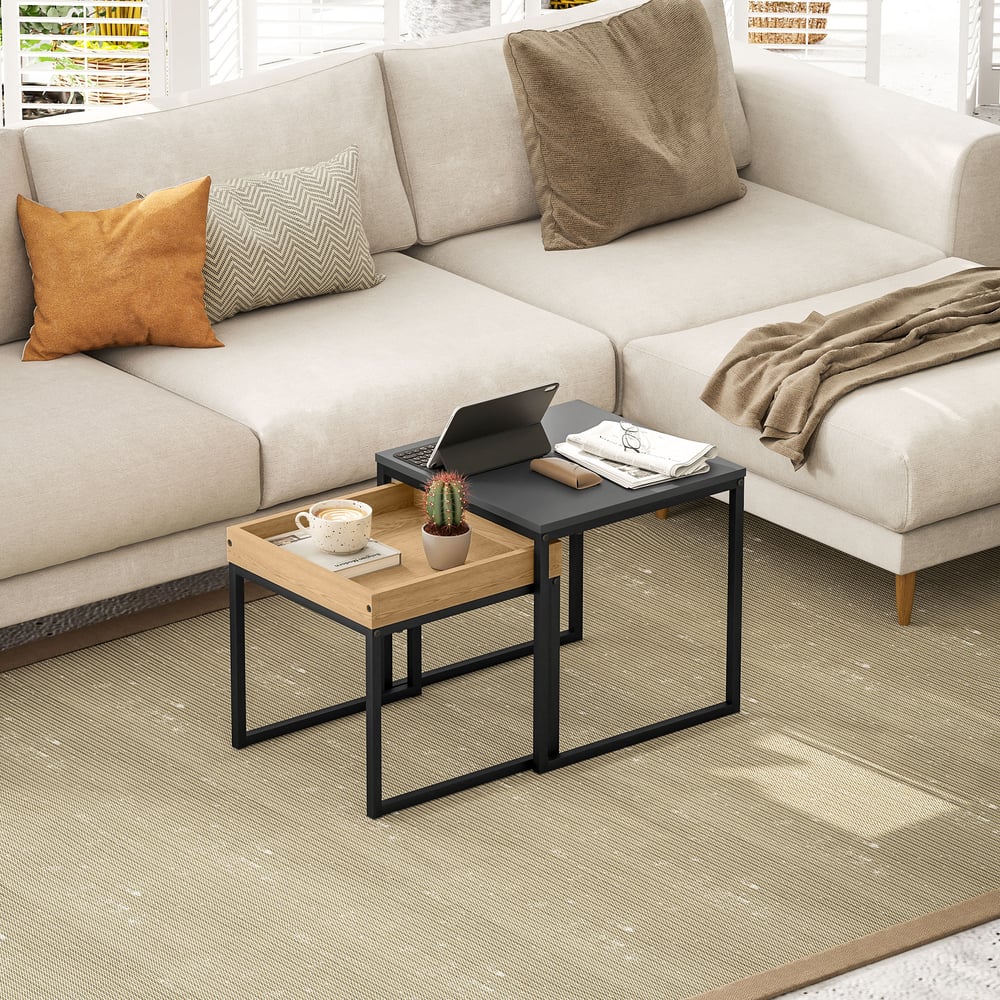 The nesting coffee tables are placed in a lounge area with a laptop and tablet