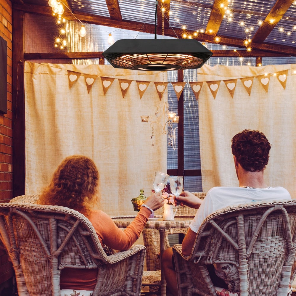 The electric patio heater suspended from a ceiling over a table with two people sitting