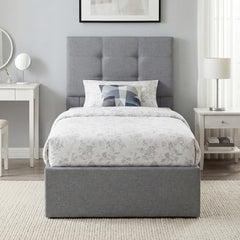 The grey ottoman bed made up with bedding in a bedroom setting