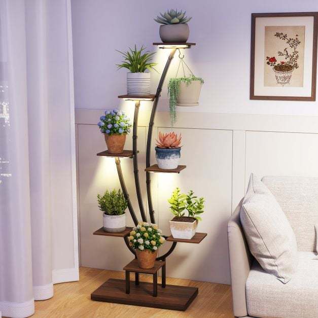 The plant stand positioned in a corner of a room with various indoor plants on the shelves