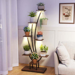 The plant stand positioned in a corner of a room with various indoor plants on the shelves