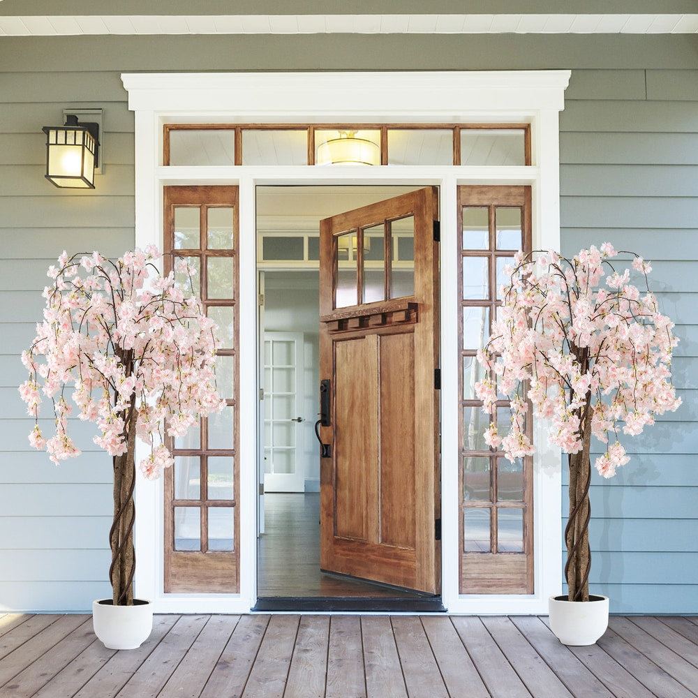 Two artificial cherry blossom trees with white pots flanking a doorway