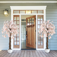 Two artificial cherry blossom trees with white pots flanking a doorway