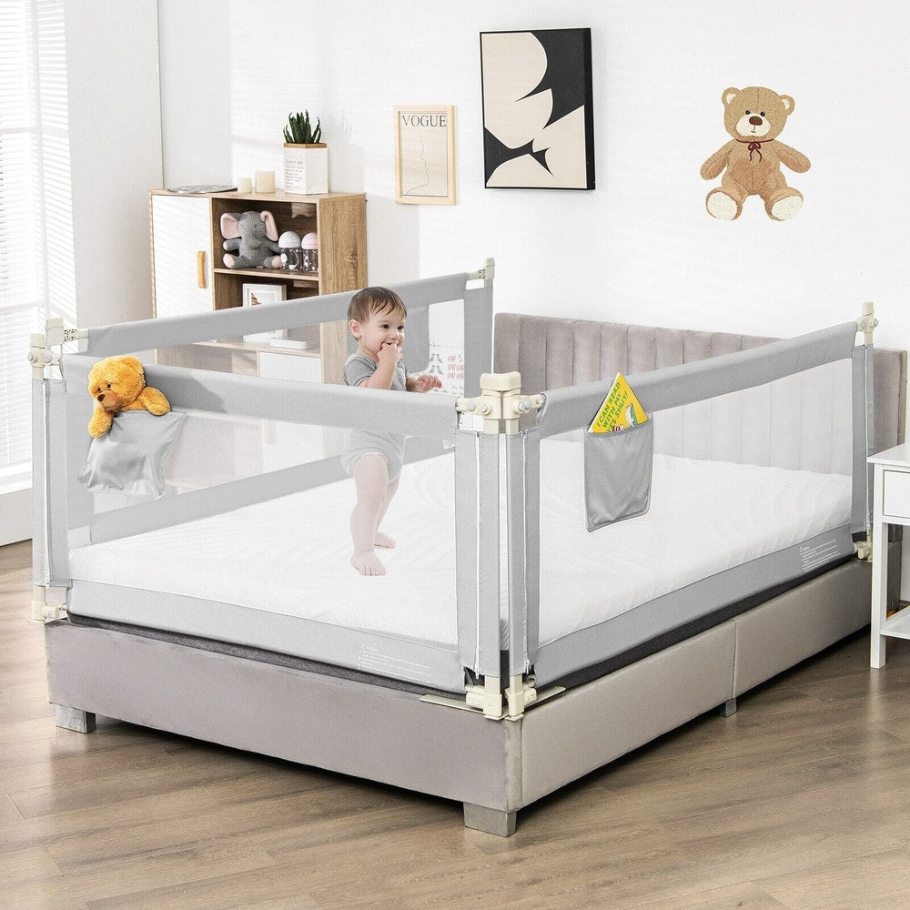 The grey bed guardrail on a mattress with a baby and toys