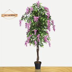 A single artificial tree with pink flowers indoors on a wooden floor