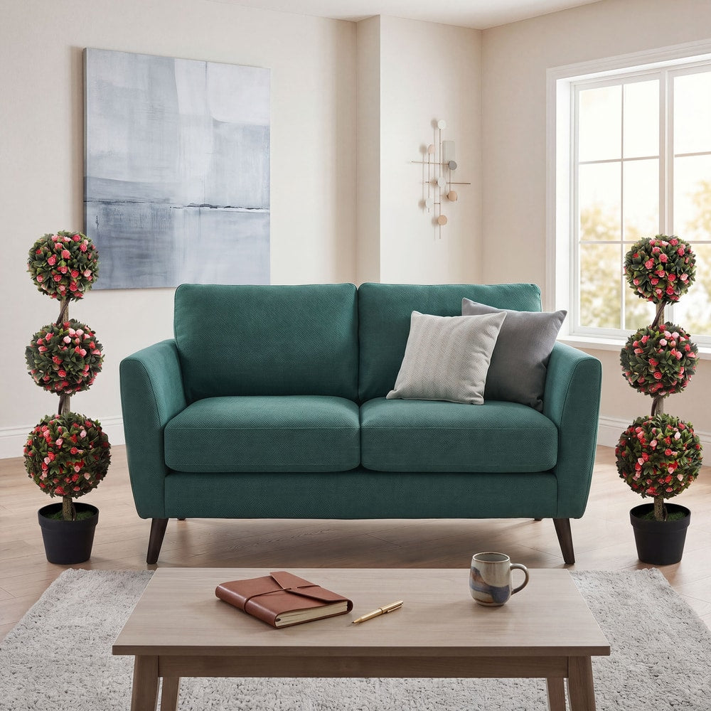 Two artificial rose topiary trees placed either side of a sofa in a living room