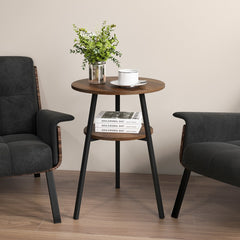 The end table positioned between two dark armchairs with a plant and cup on the tabletop