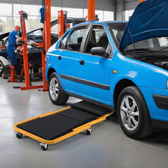 Rolling creeper seat laid flat next to a blue car in a workshop