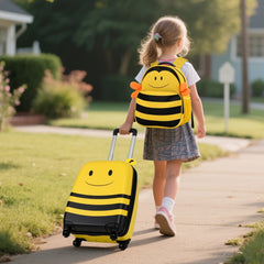 The kids luggage being pulled by a young child walking along a pavement outdoors