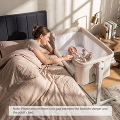 Mother and baby interacting next to the bedside sleeper in a bedroom