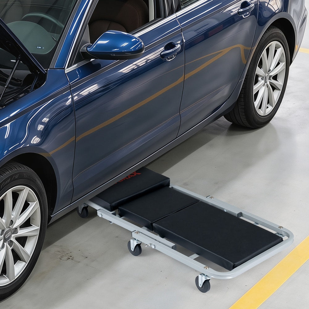 The flat mechanic creeper positioned underneath the side of a car for maintenance access