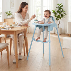 Baby eating at a table in the blue convertible high chair with a woman feeding them