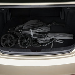 Folded grey double pushchair stored in the boot of a car
