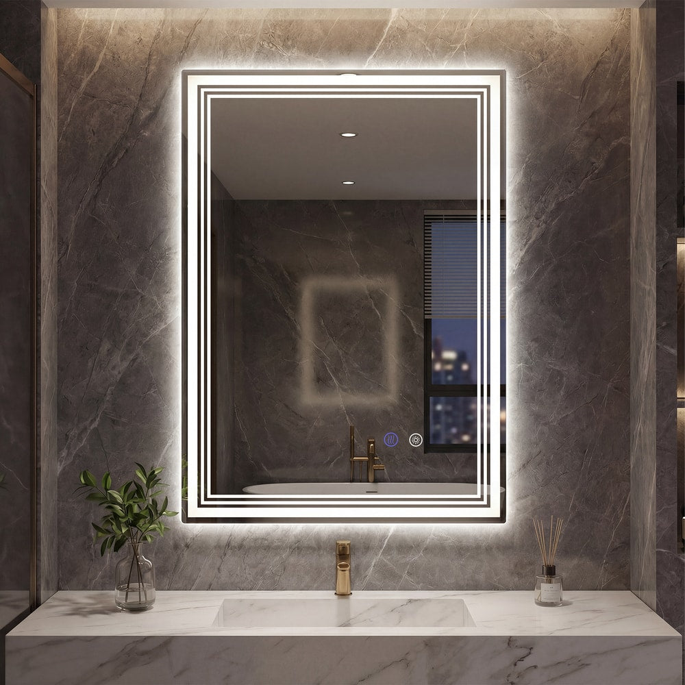 The illuminated bathroom mirror hanging on a dark marble wall above a washbasin
