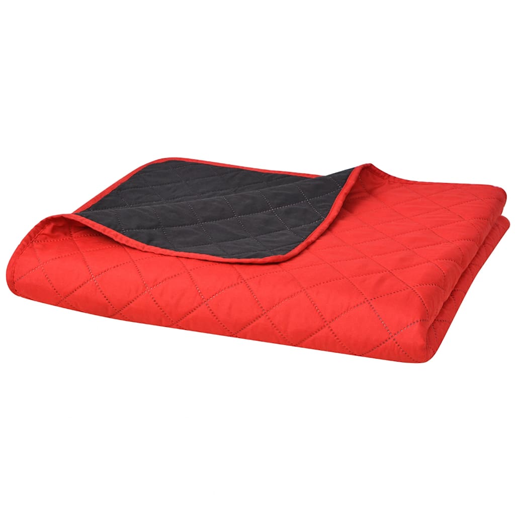 The folded quilted bedspread showing the red top side and the black underside