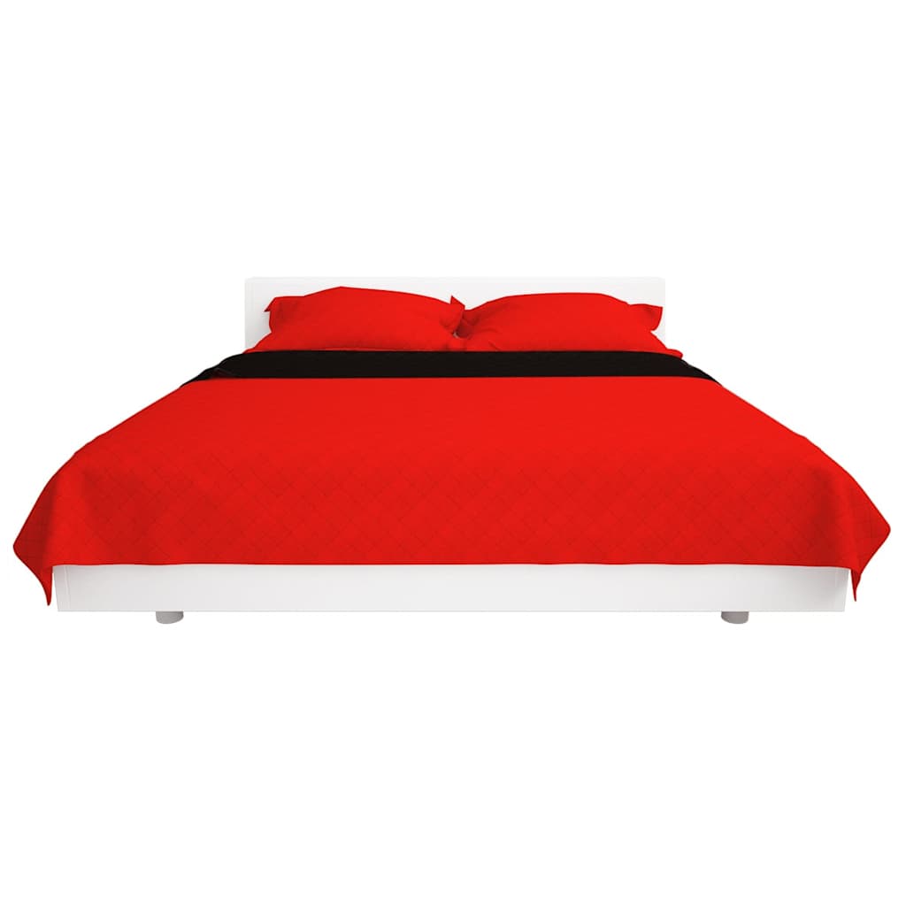 The quilted bedspread in red draped over a bed with a black accent strip