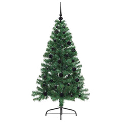 The green artificial Christmas tree with black baubles and lights, slightly angled