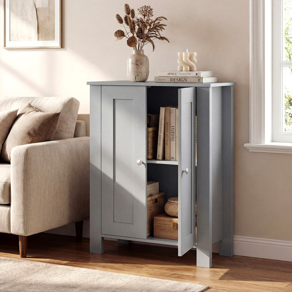 The freestanding wooden storage cabinet in grey in a living room setting with books and a vase