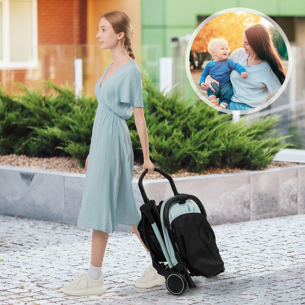 The baby stroller folded and being carried by a woman walking along a stone path