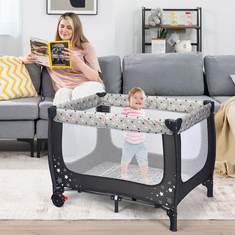 The baby playpen in a living room with a toddler standing inside on the lower base level