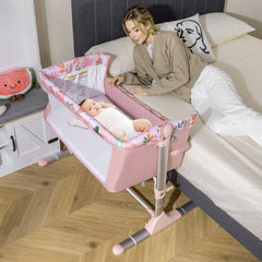 Pink bedside sleeper with a baby lying in it, next to a bed with a woman