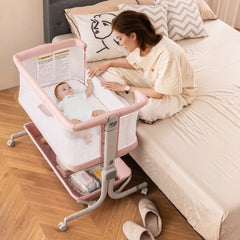 The bedside sleeper is next to a bed with a baby inside and a woman sitting on the bed