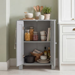 The grey cabinet with double doors open showing kitchen items like jars and pots