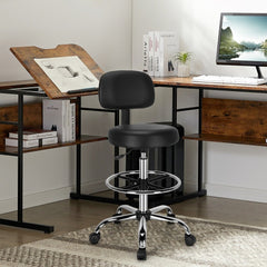 The drafting chair is positioned at a drawing desk in a home office environment
