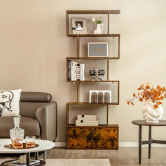 A rustic brown bookcase with cabinet styled with books and decorative items next to a sofa