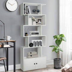 The white bookcase with cabinet shown in a living room setting next to a desk and a plant