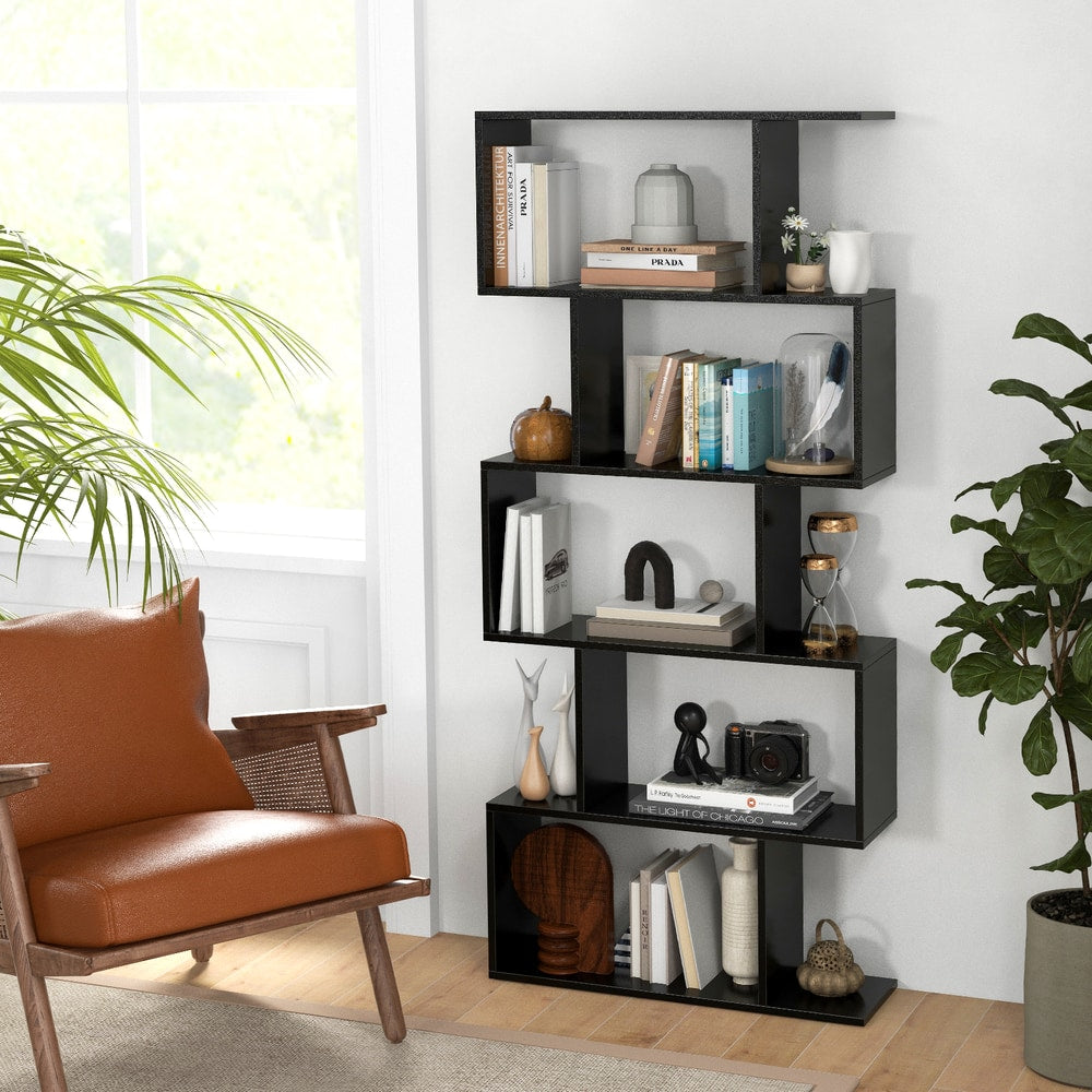 The S-shaped bookcase in a bright room with a leather armchair and plants