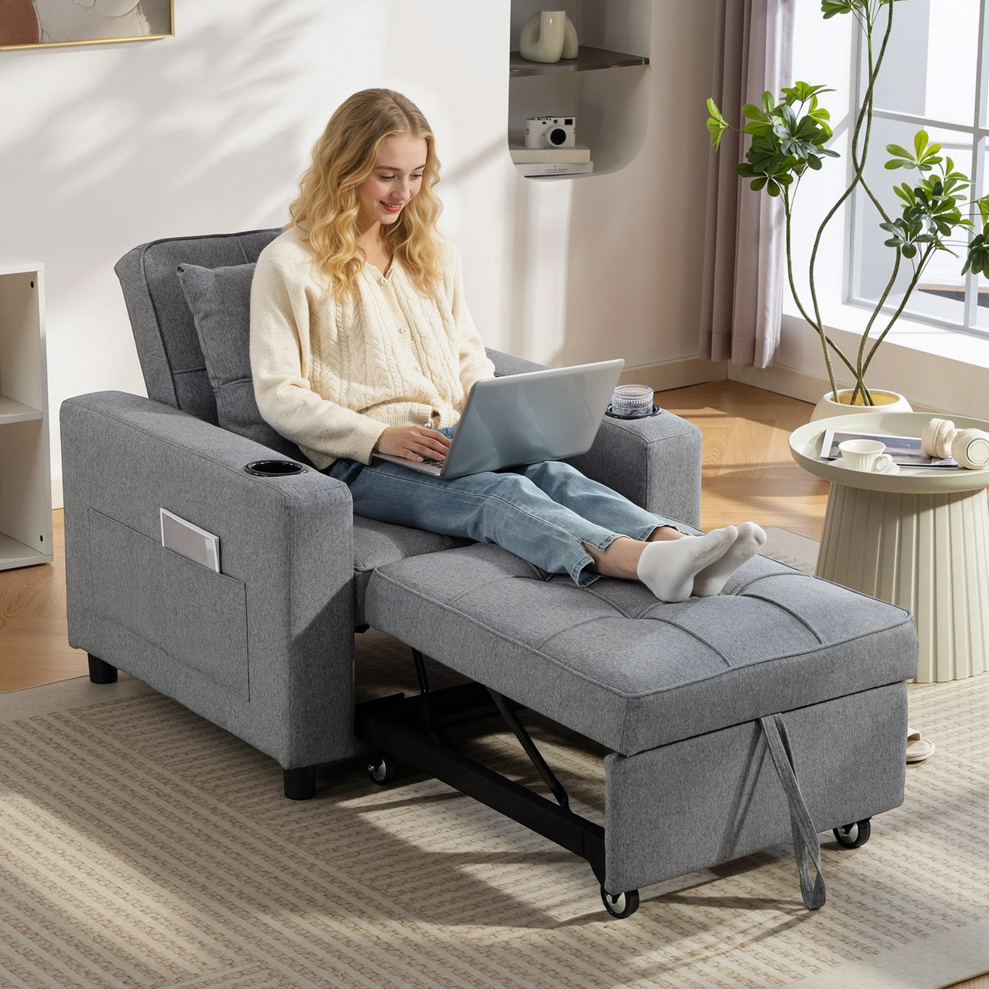 Woman using a laptop on a gray recliner chair in a bright living room.