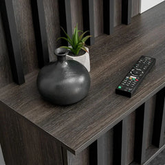 The entertainment unit surface holds a small decorative vase and a black television remote control