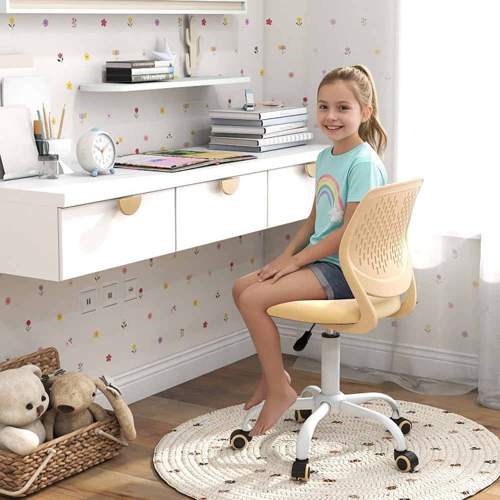 A young girl sits comfortably on the yellow kids chair with adjustable height at her desk