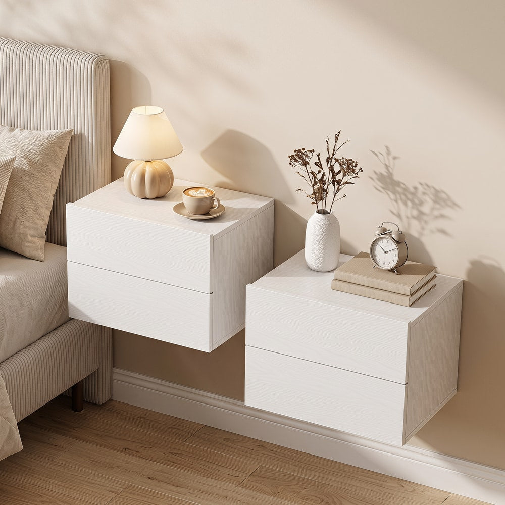 Two white bedside cabinets with drawers mounted on a wall next to a bed