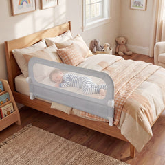 The foldable bed rail in use on a toddler bed with a baby sleeping