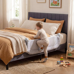 A toddler climbing over the bed rail onto a bed