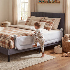 The bed rail attached to a single bed, a toddler climbing over it