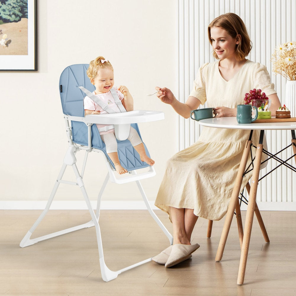 A mother feeding her baby in the navy blue high chair at a dining table