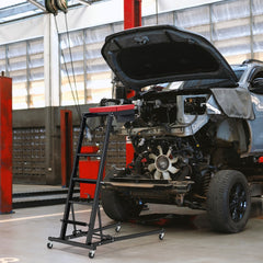 Automotive engine creeper positioned next to a car engine bay with the bonnet open