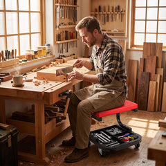 Man using the rolling stool with tool tray while working on wood in a workshop
