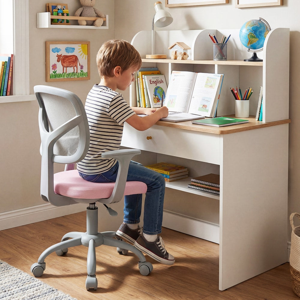 A young boy sits at a desk using the pink kids desk chair