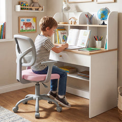 A young boy sits at a desk using the pink kids desk chair