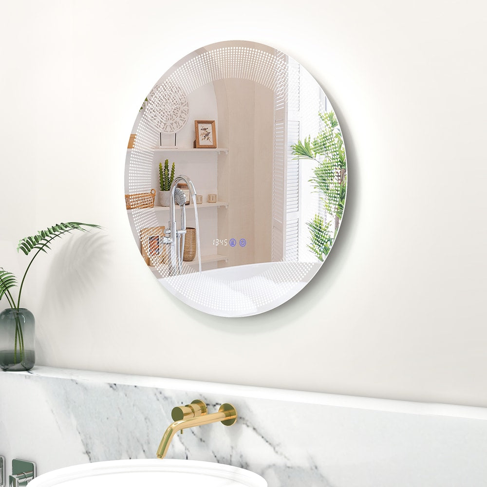 The glowing circular mirror fixed to a white wall above a marble vanity with gold tap