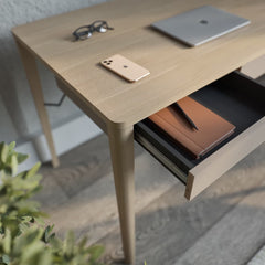 The workspace desk showing a close up of the open drawer with a notebook and pen inside