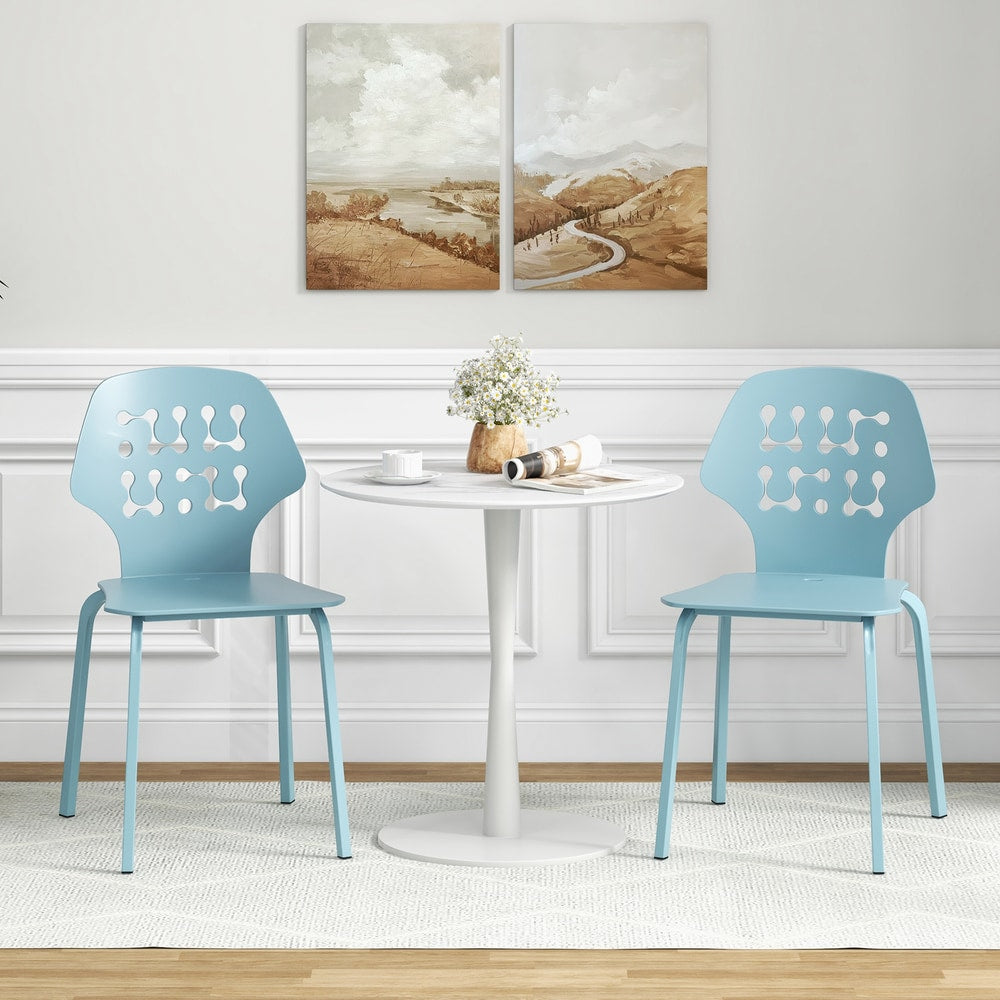 Two blue metal dining chairs with hollowed backrests beside a white table