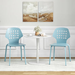 Two blue metal dining chairs with hollowed backrests beside a white table