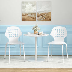 Two white metal dining chairs with hollowed backrests next to a table